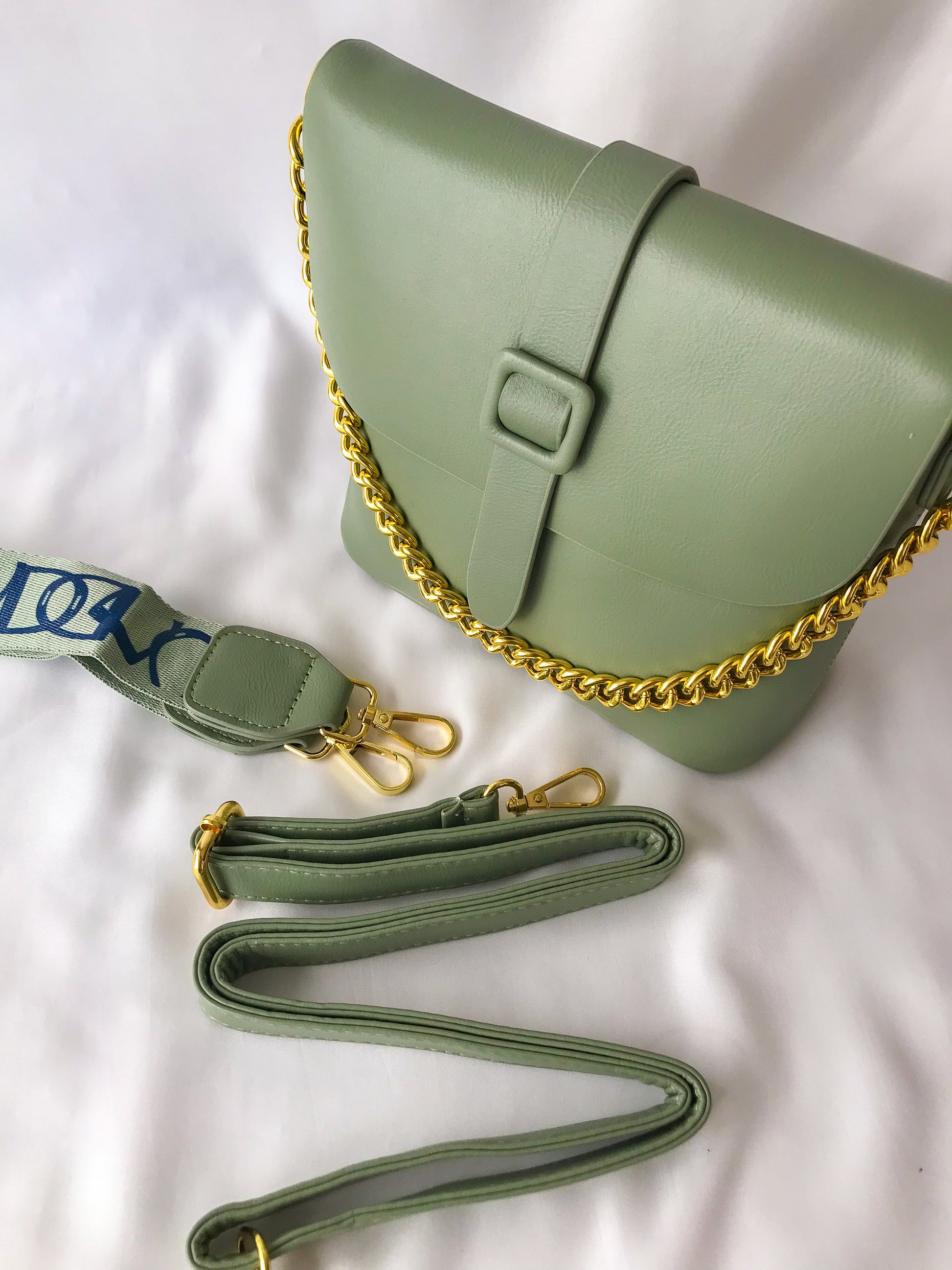 cartera tipo crossbody verde con cadena decorativa y strap